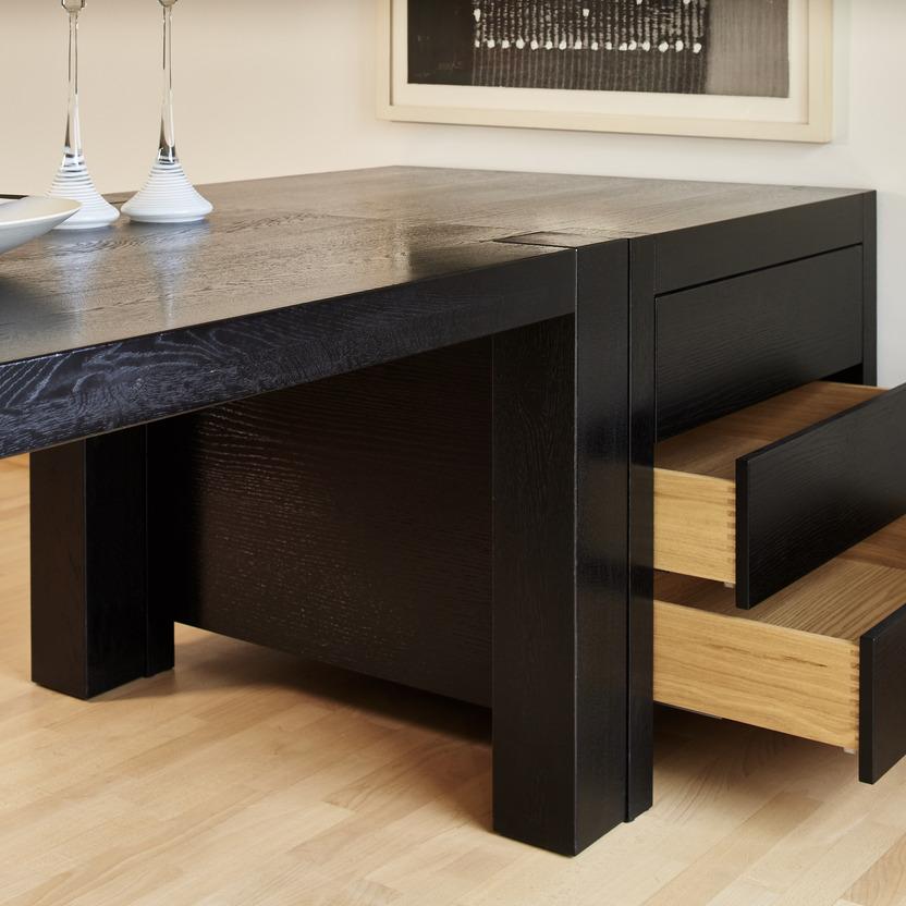 Geöffnete Schubladen eines maßgefertigten, schwarzen Tisches mit klarer Linienführung. Die Innenseiten der Schubladen bestehen aus hellem Massivholz mit präziser Fingerzinkung.