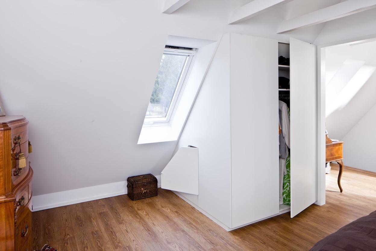Kleiderschrank nach Maß unter Dachschräge mit minimalistischer Front Individuell gefertigter Kleiderschrank nach Maß in einem Schlafzimmer unter der Dachschräge. Weiß lackierte Fronten ohne Griffe und passgenaue Schranklösung mit cleverem Staufach unterhalb des Dachfensters.