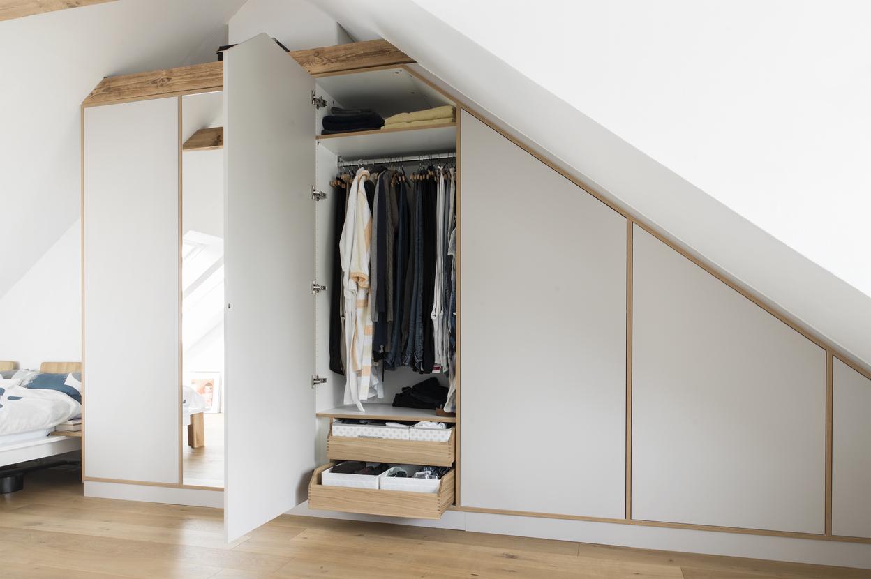 Kleiderschrank nach Maß unter Dachschräge mit offener Spiegeltür Maßgefertigter Kleiderschrank mit Spiegeltür und Kleiderstange, eingebaut unter einer Dachschräge im Schlafzimmer.
