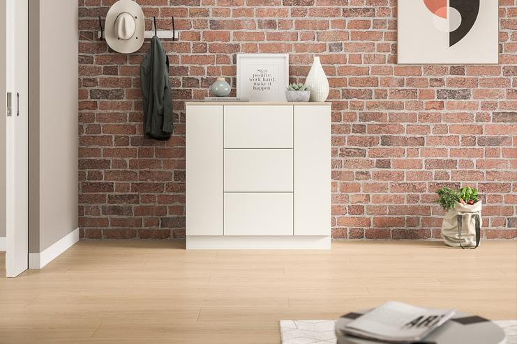 Eine schlichte, weiße Kommode nach Maß, die sich gegen eine rustikale Backsteinwand abhebt, bietet Stauraum und eine stilvolle Ablagefläche im Eingangsbereich.